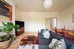 A living room with a sofa, coffee table, TV, potted plants, and a staircase leading to another room. - The Sun Deck Townhouse (Greater London)