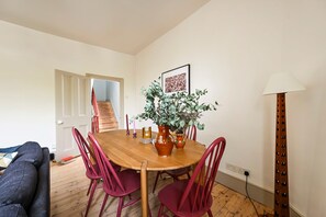 A dining area with a wooden table, red chairs, a potted plant, and a lamp. - The Sun Deck Townhouse (Greater London)