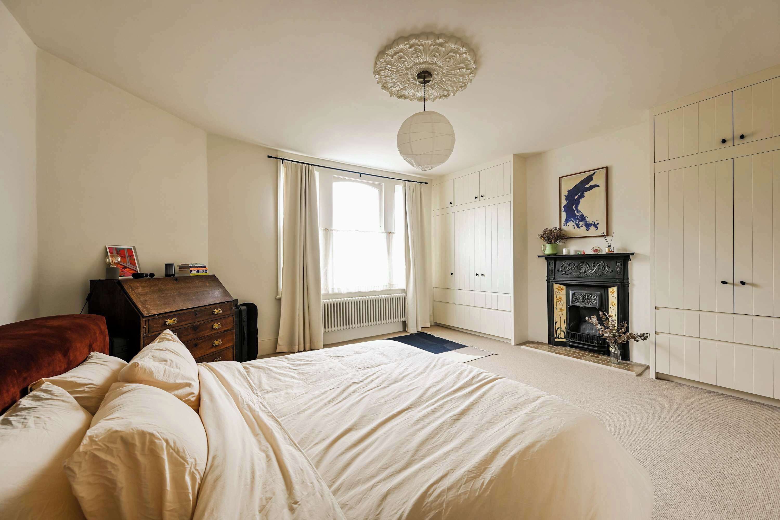 A bedroom with a bed, a dresser, a fireplace, and a wardrobe.