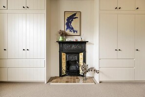 A room with a fireplace, a framed artwork above it, and a vase with flowers on the mantel. - The Sun Deck Townhouse (Greater London)