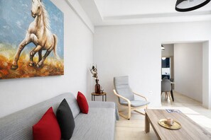 Un salon moderne comprenant un canapé, un fauteuil, une table basse et un tableau représentant un cheval.