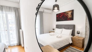 Una habitación de hotel moderna con una cama, mesitas de noche, un espejo y un cuadro.