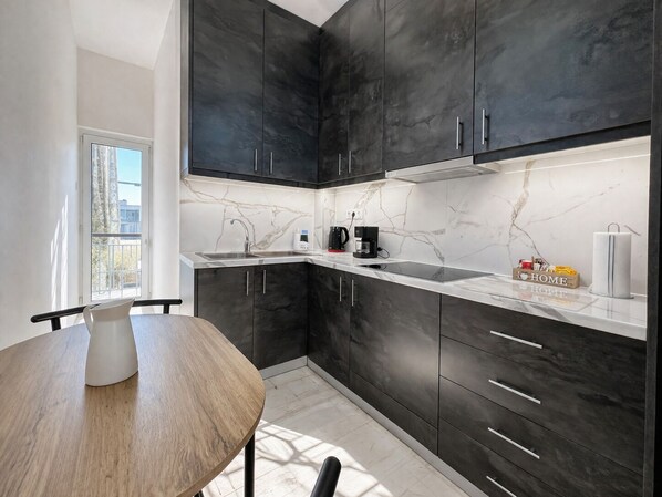 Une cuisine moderne avec des meubles de couleur sombre, un plan de travail blanc et un pare-feu en marbre.