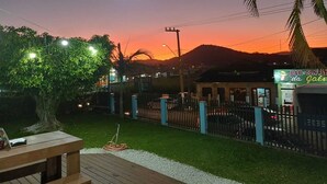 A patio with a table and chairs, a tree, and a fence. - Pousada Sonho Meu - Penha (Penha)