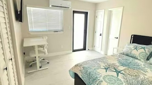 Een slaapkamer met een bed, een plafondventilator, een raam met zonwering, een airconditioning en een deur.