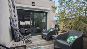 Een terras met buitenmeubilair, een zwembad en een gebouw met een glazen deur.