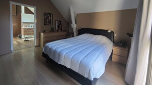 Een slaapkamer met een bed, een kaptafel, nachtkastje en uitzicht op de gang.