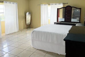 Une chambre à coucher avec un lit, une commode, un miroir et des rideaux.