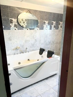 Une salle de bain moderne avec une baignoire sur pieds, un grand miroir et un mur recouvert de carreaux.
