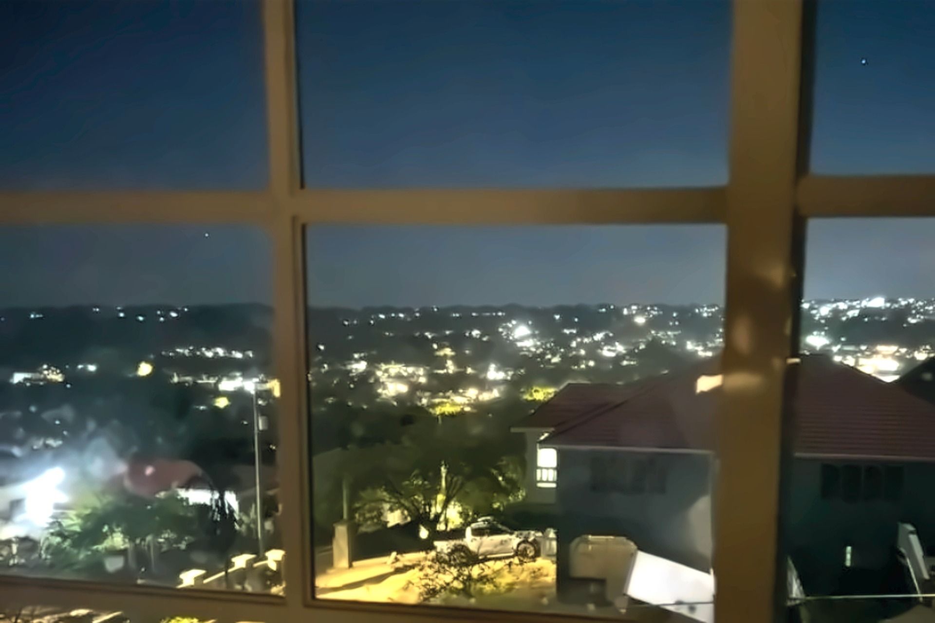Una finestra con vista su un panorama urbano notturno, con edifici e lampioni.