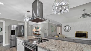 A modern kitchen with stainless steel appliances, a marble countertop, and a built-in oven.