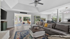 A spacious living room with a gray sofa, a coffee table, and a ceiling fan.
