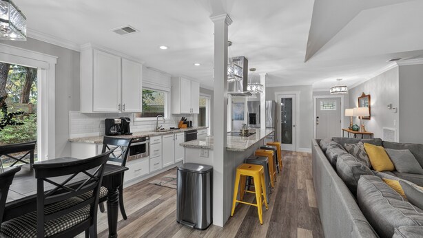 A modern kitchen with white cabinets, a central island, and a dining area with a table and chairs.