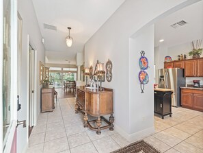 A spacious kitchen with modern appliances, a dining area with a wooden table, and a hallway leading to a conservatory. - Charming Large 3-bedroom 2 bath house in The Villages. (The Villages)