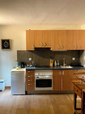A compact kitchen with wooden cabinets, a built-in oven, and a dishwasher.