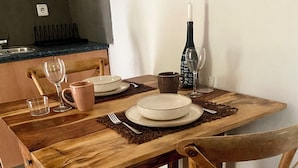 A wooden dining table with a woven placemat, a wine bottle, and a glass. - Forest retreat, close to Barcelona and Beaches (Dosrius)