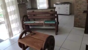 A spacious room with a wooden bench, a dining table, and a kitchen area.