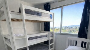 A room with bunk beds, a single bed, a view through a window, and a white carpet. - Magnificent apartment in a private residence for 8 people, 5 minutes from Lyon, view of Part Dieu (Bron)