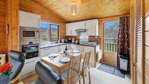A wooden cabin with a kitchen, dining area, and a view of the outdoors.