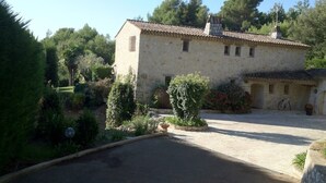 A stone building with a tiled roof, surrounded by greenery and a paved driveway. - Lovely family villa in Saint Paul de Vence (La Colle-sur-Loup)