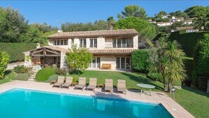 A house with a swimming pool, a patio with lounge chairs, and a well-maintained garden. - Lovely family villa in Saint Paul de Vence (La Colle-sur-Loup)