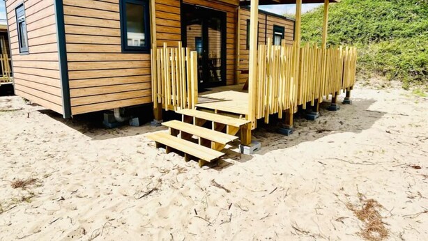 A wooden cabin with a covered porch and steps leading to the entrance. - Camping Cristal d'Opale (Dannes)