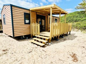 A wooden cabin with a covered porch and steps leading to the entrance. - Camping Cristal d'Opale (Dannes)