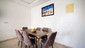A dining area with a wooden table, six chairs, and a bowl of fruit. - Cozy Stay in Modern Apt / Clean Comfortable & Calm (Imi Ouaddar)