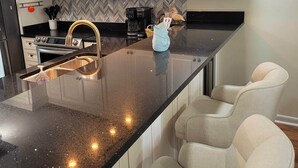 Een moderne keuken met een centraal kookeiland, roestvrijstalen apparatuur en een backsplash in een herringbone-patroon.