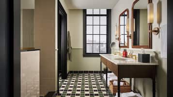 A bathroom with a checkered floor, a window with a city view, a sink with a mirror, and a towel rack.