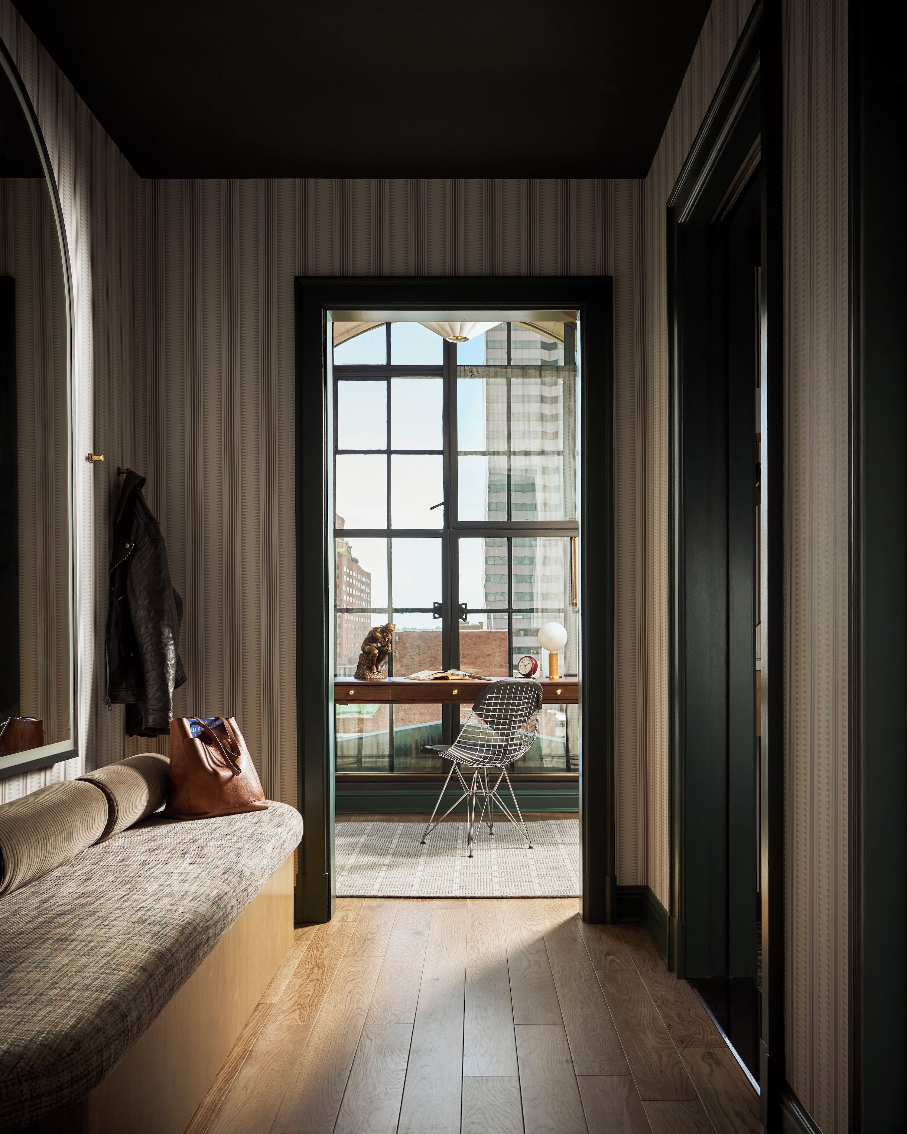 A room with a large window, a desk, a chair, and a sofa.