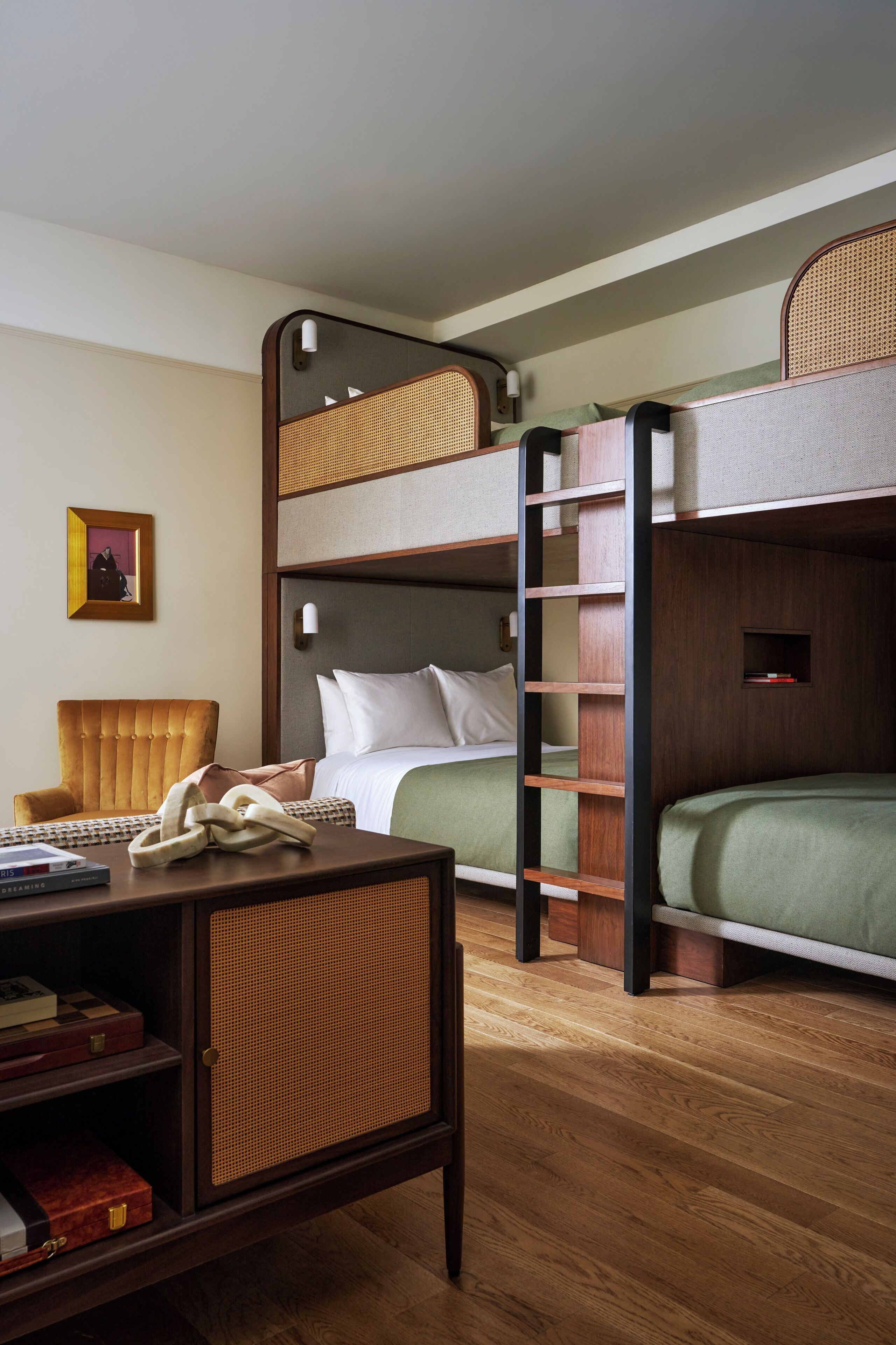 A bunk bed room with a desk, chair, and a framed picture on the wall.