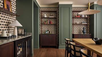 Un comedor con una mesa y sillas de madera, una estantería y una zona de cocina con encimera y armarios.