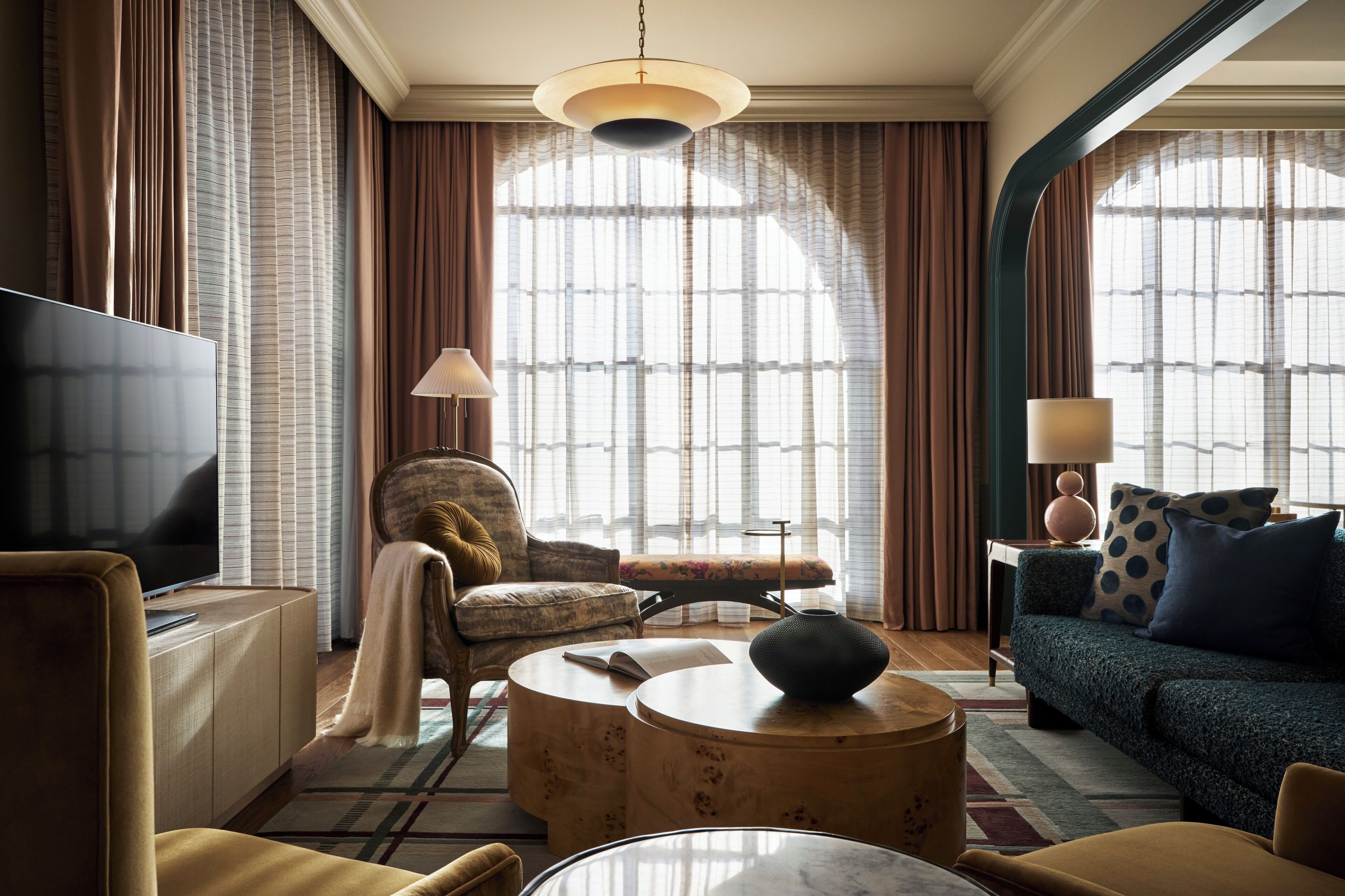 A modern living room with a flat-screen TV, a sofa, a chair, a coffee table, and a lamp.