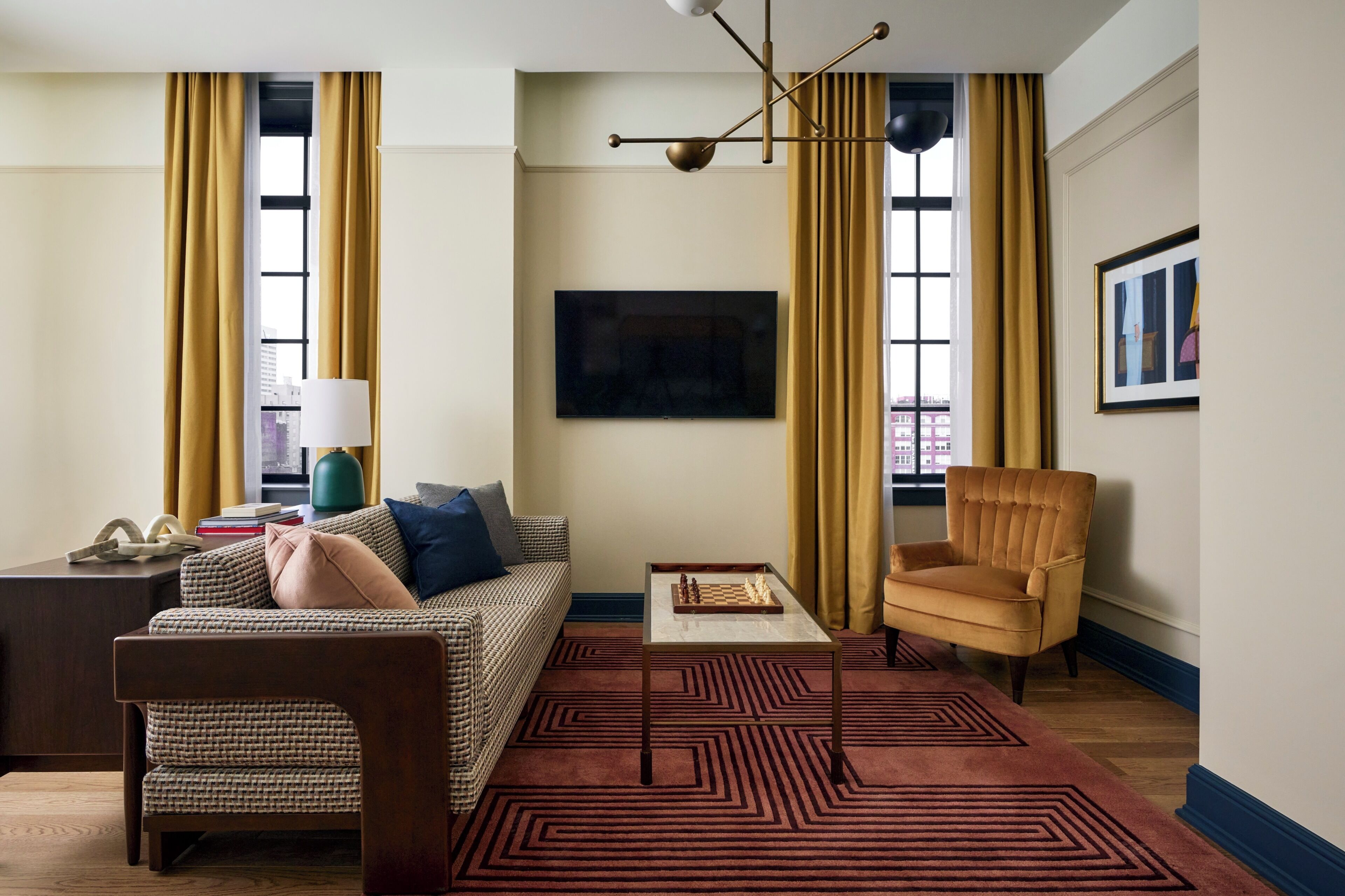 Ein Wohnzimmer mit einer Couch, einem Sessel, einem Couchtisch und einem gemusterten Teppich.