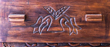 A wooden cabinet with intricate carvings and two metallic handles.