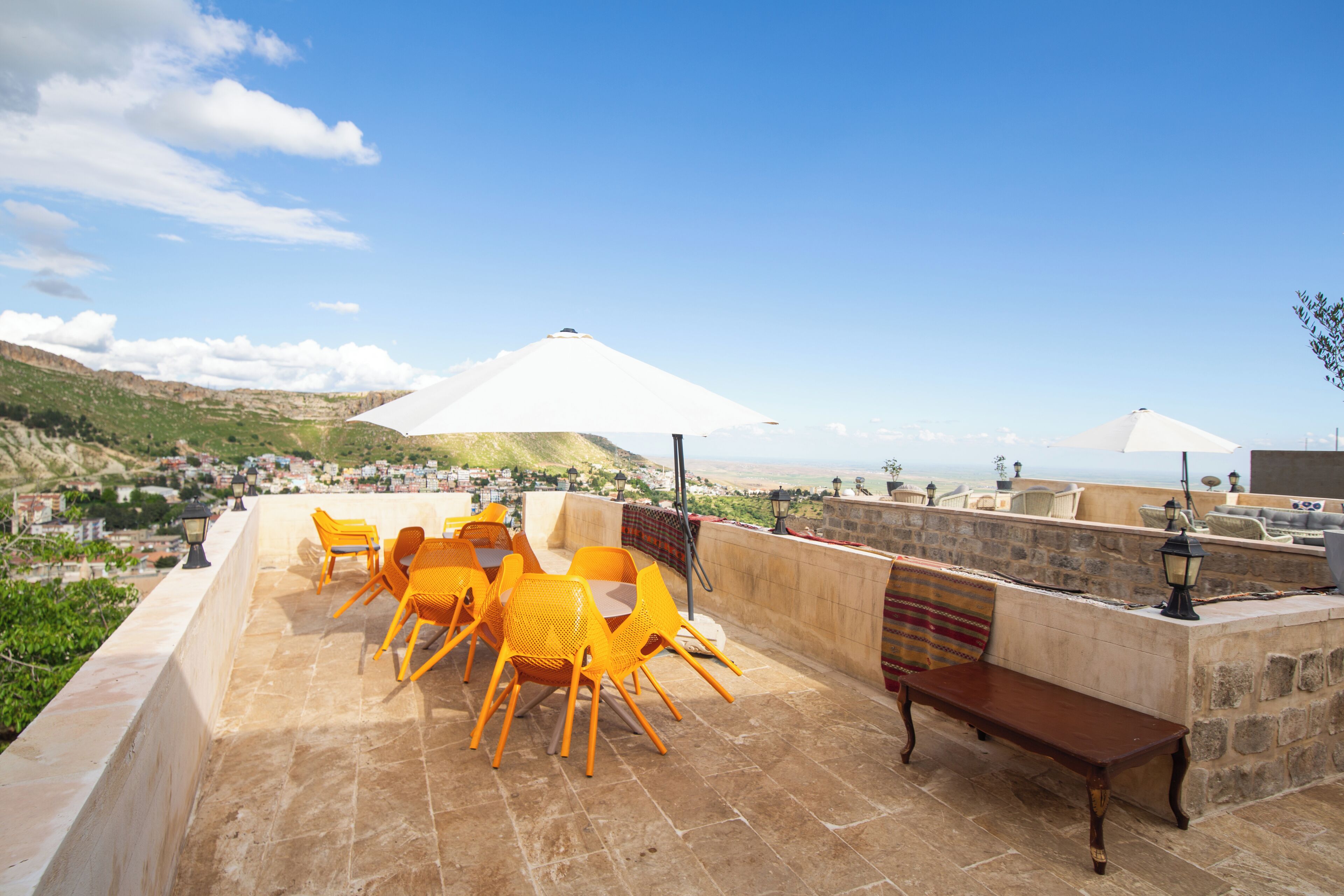 A terrace with outdoor seating, stone walls, and a view of the landscape.