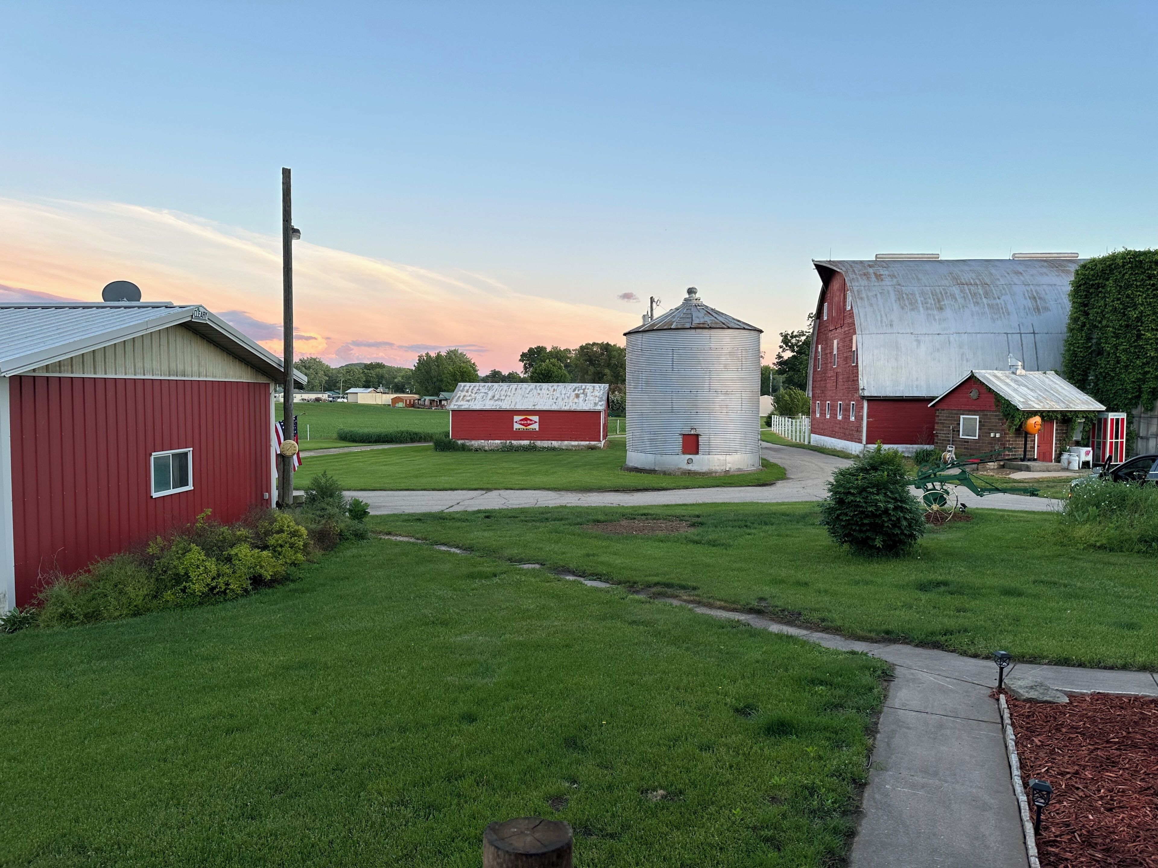 Un paysage rural avec des granges, une tour à grain et un ciel dégagé.