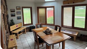 A dining area with a wooden table, chairs, and benches, a skylight, and windows with blinds. - Experience a Farm getaway! (Bagley)