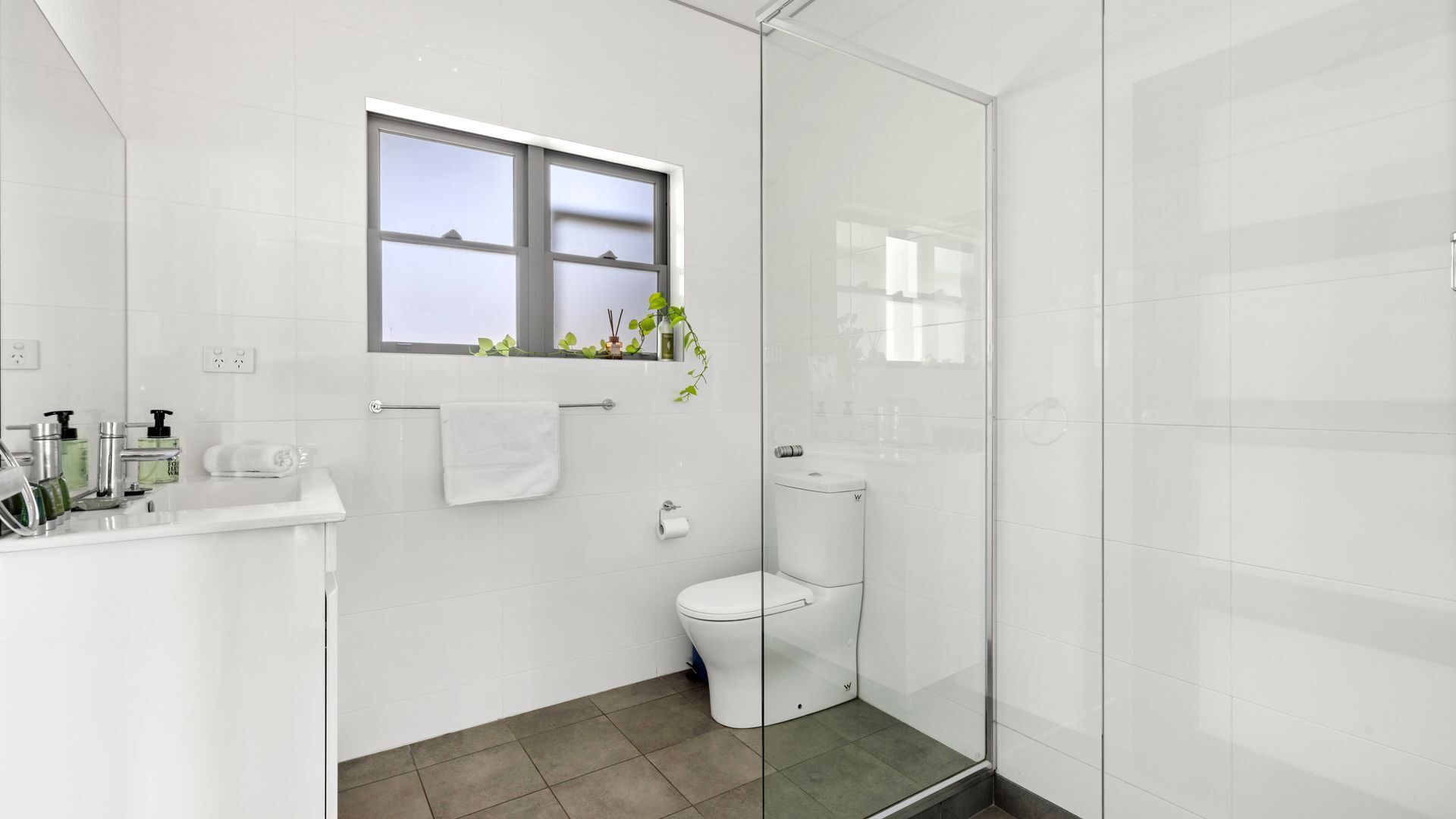 A modern bathroom with a toilet, sink, and shower area.