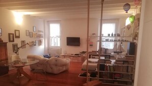 A living room with a sofa, a television, a bookshelf, and a dining table.