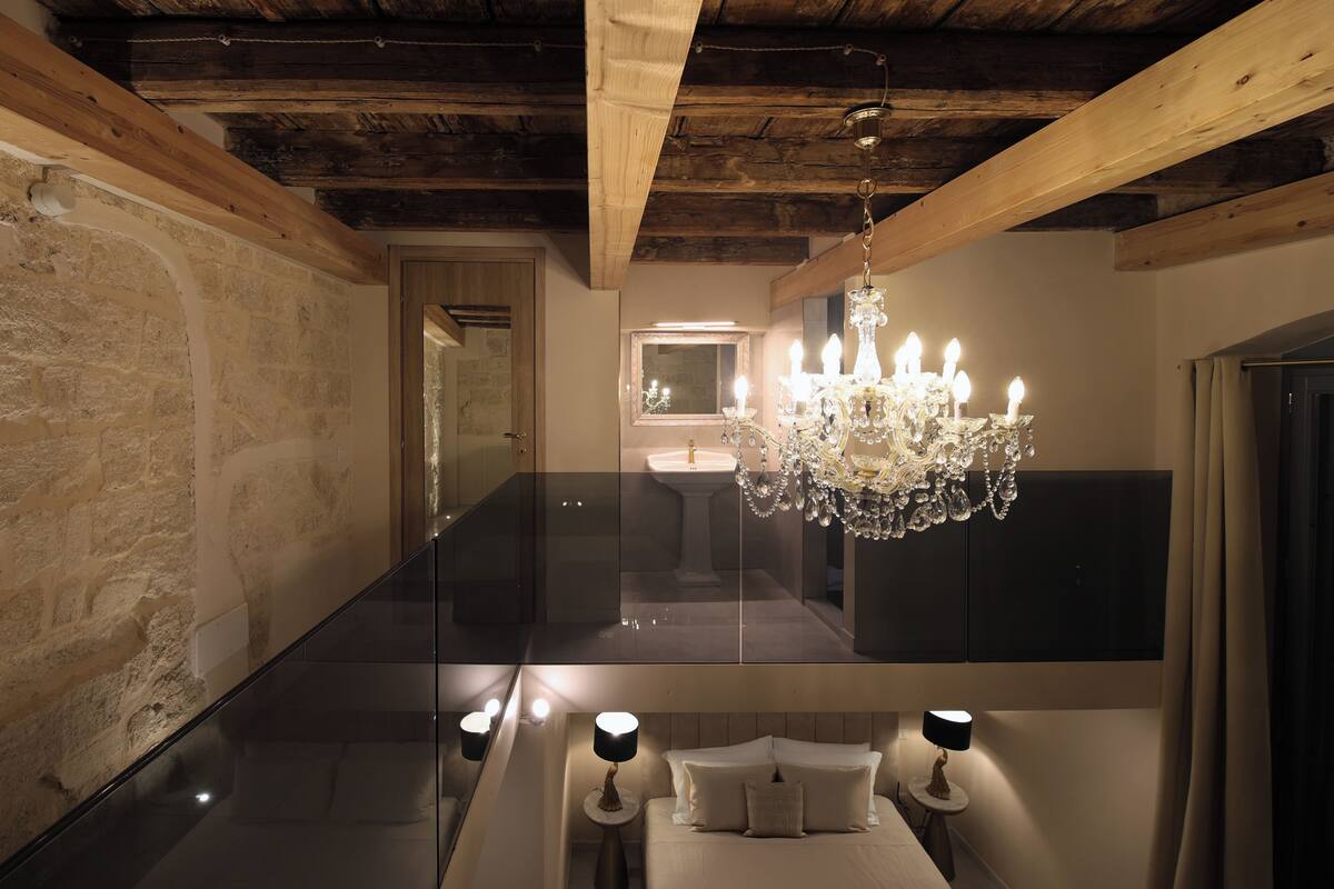 Une chambre à coucher avec un lit, des lampes de chevet, un lustre, un miroir et un plafond en bois.