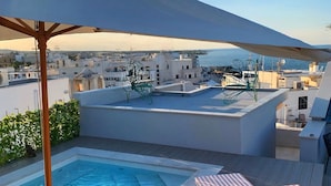 A rooftop pool area with a view of the city and sea, two lounge chairs, and a large umbrella. - The Duchess of Puglia (Polignano a Mare)