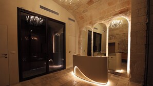 A modern reception area with a curved reception desk, large arched windows, and a chandelier. - The Duchess of Puglia (Polignano a Mare)