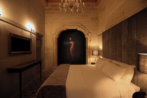 A hotel room with a bed, a television, a chandelier, and a statue. - The Duchess of Puglia (Polignano a Mare)