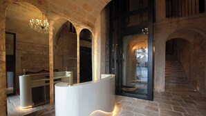 A reception area with a modern reception desk, stone walls, and a chandelier. - The Duchess of Puglia (Polignano a Mare)