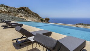 Ein Poolbereich mit Liegestühlen und Meerblick.