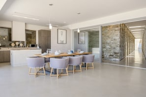 Una cucina moderna con zona pranzo, parete in pietra e vista sul corridoio.