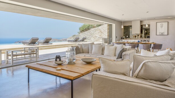 Ein modernes Wohnzimmer mit Meerblick, einem Holztisch und einer Sitzecke.