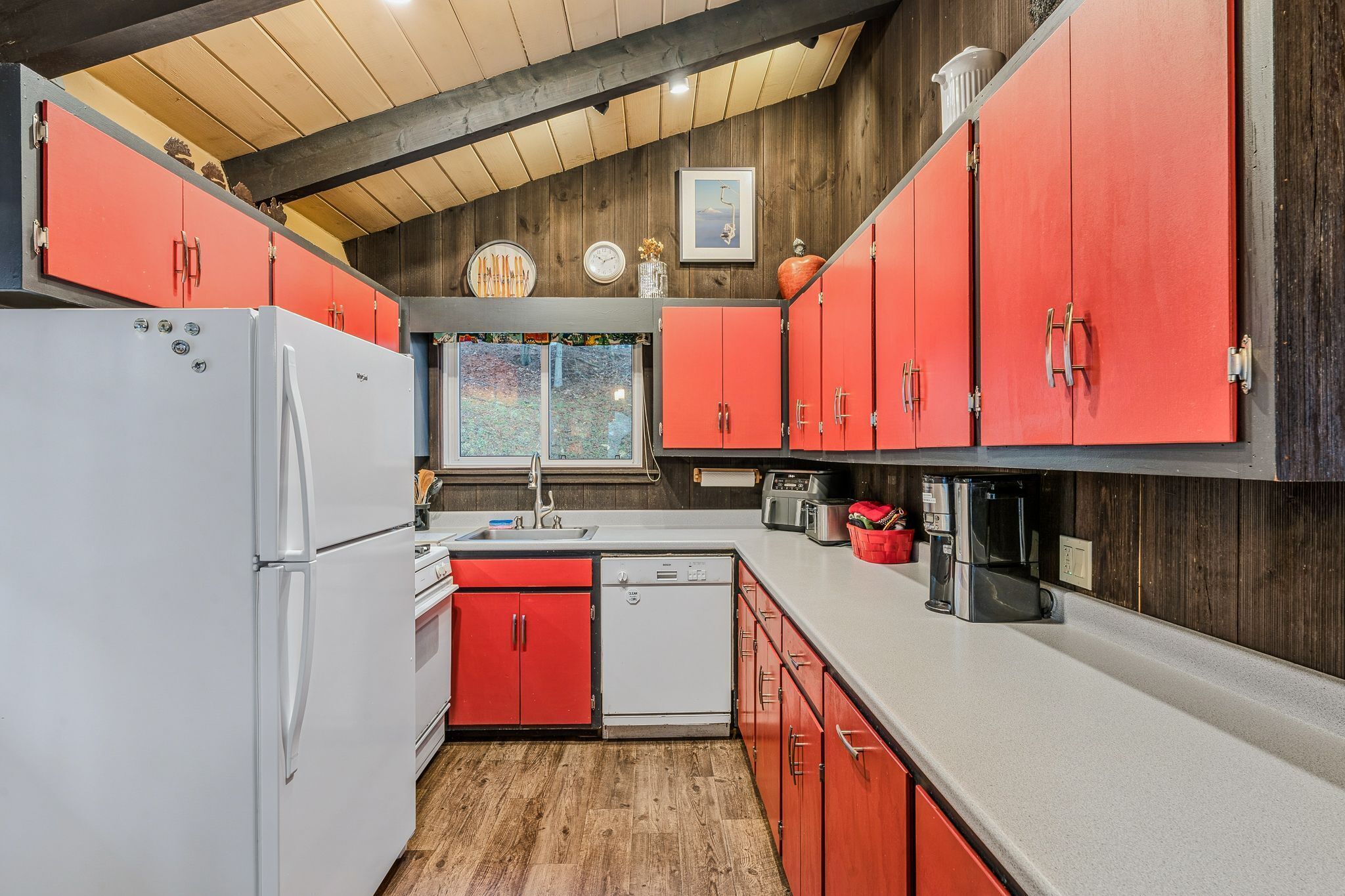 Una cocina con armarios rojos, un refrigerador blanco y una cafetera.